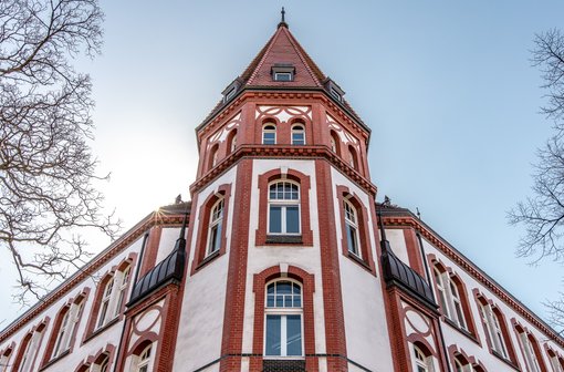 Das IFSH Hauptgebäude - Ein rot-weißes Fachwerkgebäude mit einem spitzen Turm, von unten gesehen.
